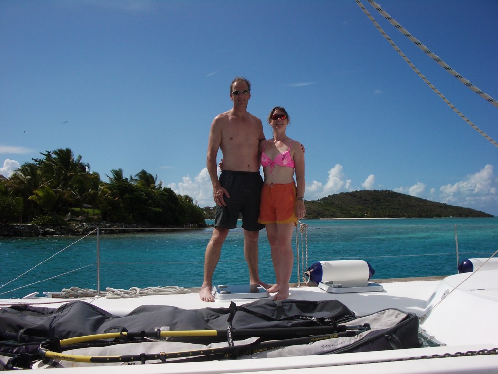 Aithor Jacqueline Lambert with husband Mark aboard a catamaran in the British Virgin Islands, with a bright marine background wearing bright clothes
