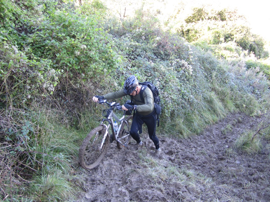 Jacqueline Lambert's husband Mark pushing a bicycle up a very muddy hill